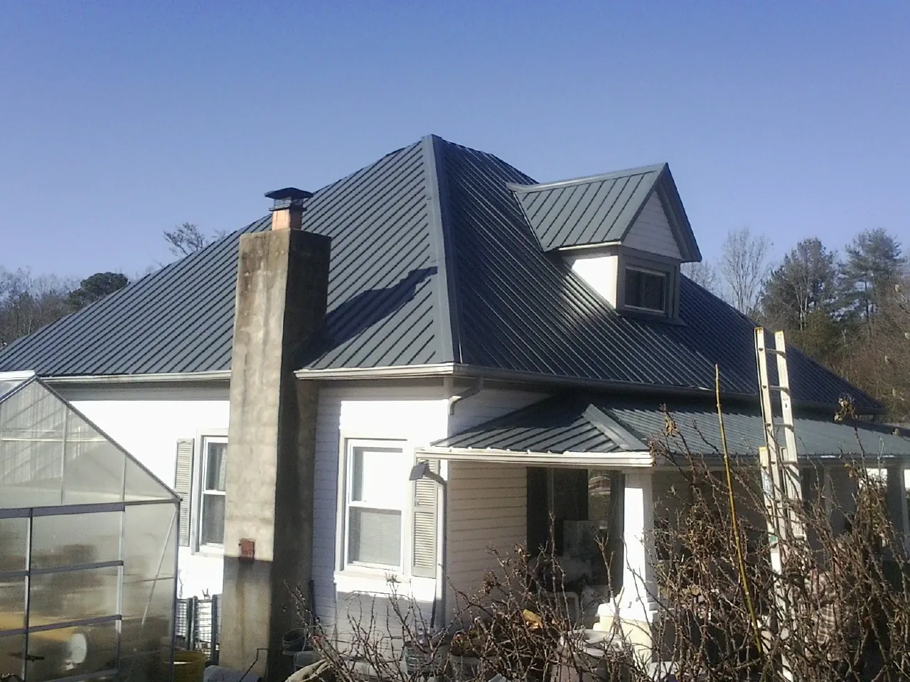 Dark blue standing seam metal roof on a white farmhouse with dormer — Slate & Tile Roof Repair by Roofing Brothers in Parsippany