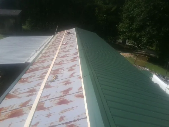 Old rusted panels beside newly installed green metal roofing — Wind Damage Roof Repair by Roofing Brothers in Parsippany