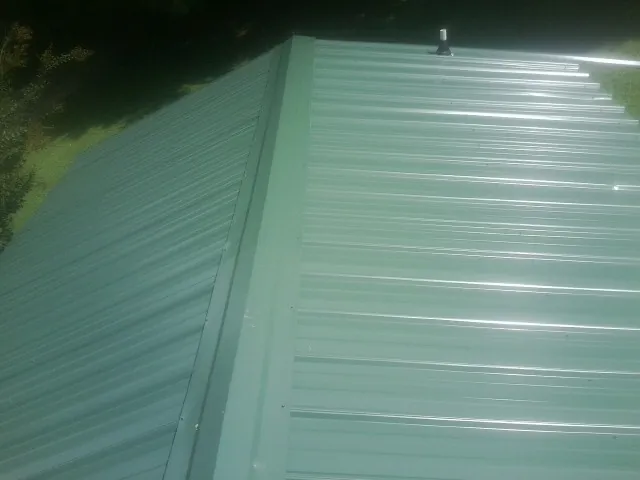 New green metal panels meeting at the ridge of a roof — Flat Roof Repair work by our crew in Parsippany