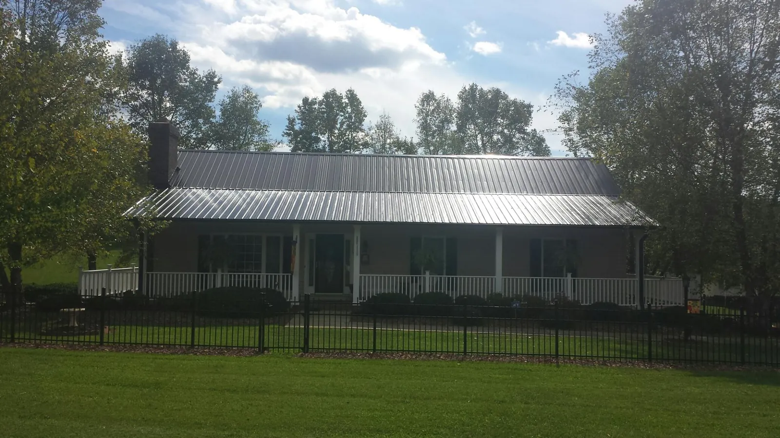 Gray metal roof on a brick ranch with a full width front porch — Gutter Guard Installation work by our crew in Parsippany