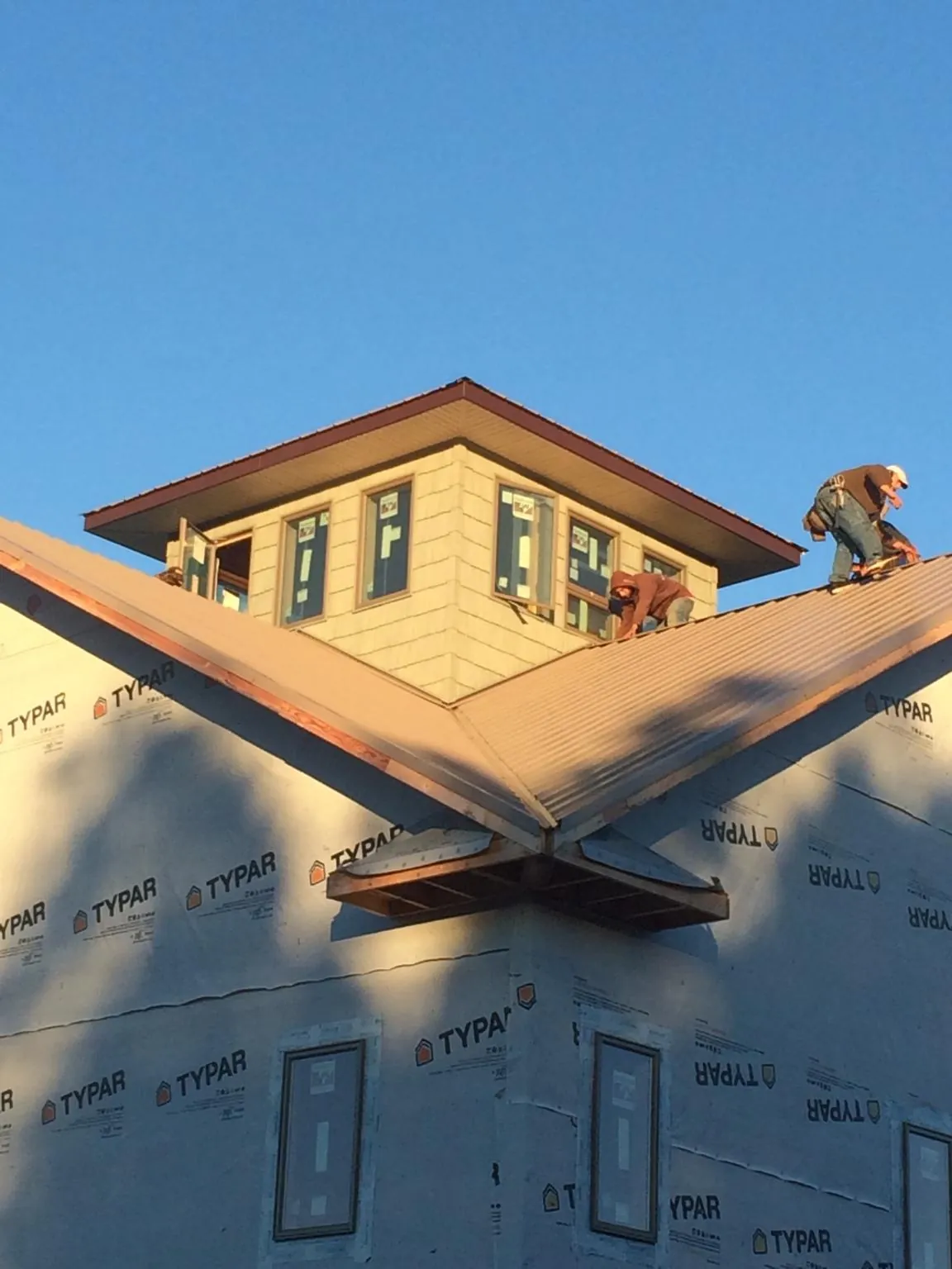 Roofers working around a rooftop cupola on a new metal roof at sunset — Roof Waterproofing in Parsippany by Roofing Brothers